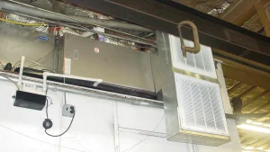 An HVAC system with Carrier and Payne branding, exposed ductwork, and electrical outlets mounted indoors.